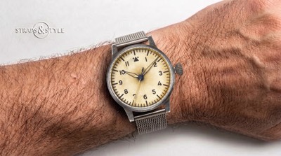 Laco pilot watch with a cream dial, dark Arabic numerals and a steel mesh bracelet on the wrist