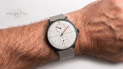Junghans Meister Regulator with a gunmetal case, pale dial, orange-filled hands, hours sub-dial at twelve and running seconds at six on a steel mesh bracelet
