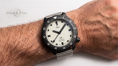 Sinn U1 diver with a cream full-lume dial, black block indices and a black-coated case and dive bezel on a Straps&Style mesh bracelet
