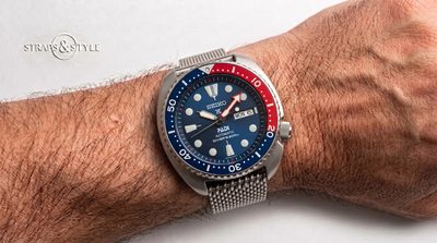 Seiko diver with a deep blue dial, red and blue rotating dive bezel, day-date at three and a steel shark-mesh bracelet