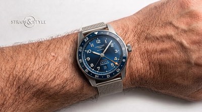 Longines Spirit Zulu Time GMT with a blue sunburst dial, blue dive-style bezel, orange arrow-tipped GMT hand and a date at six on a steel mesh bracelet