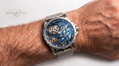 Roger Dubuis skeleton watch with a bright blue star-shaped bridge, exposed micro-rotor and brushed steel case on a Straps&Style mesh bracelet