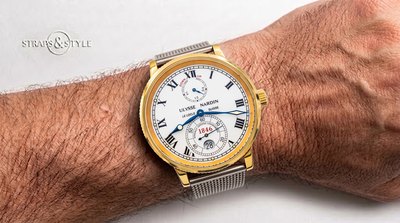 Ulysse Nardin chronometer with a gold coin-edge bezel, white dial, black Roman numerals, power reserve at twelve and small seconds with date at six on a Straps&Style mesh bracelet