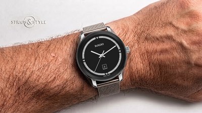 Rado watch with a glossy black dial, an inner ring set with small stones, four circular studs and a date at six on a Straps&Style mesh bracelet