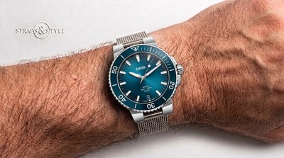 Oris Aquis Date diver with a sunburst teal dial, date at six and a matching teal rotating dive bezel on a Straps&Style mesh bracelet