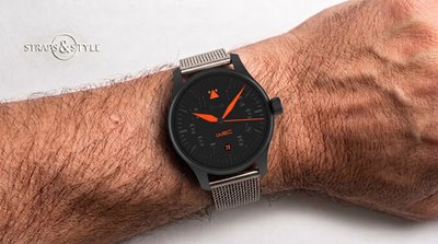 STOWA WRC pilot watch with a matte black stealth dial, orange hands, an orange pilot triangle and a round date window at six on a Straps&Style mesh bracelet
