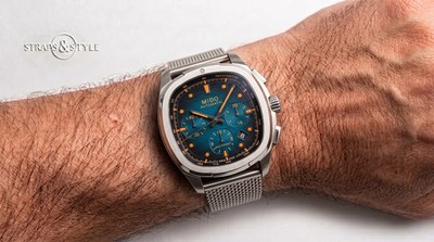 Mido Multifort TV chronograph with a blue and black textured dial, orange luminescent accents, a tachymeter chapter ring and a date at three on a Straps&Style mesh bracelet