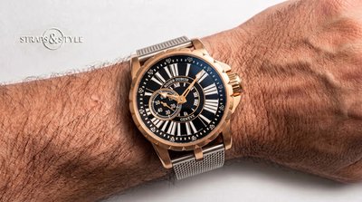 Roger Dubuis watch with a rose-gold case, fluted bezel, black dial with elongated white Roman numerals and small seconds at nine on a Straps&Style mesh bracelet