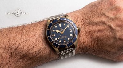 Tudor Black Bay Bronze with a dark blue dial, aged bronze case, cream lume markers and a navy blue rotating dive bezel on a Straps&Style mesh bracelet